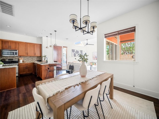 dining space with baseboards, visible vents, dark wood finished floors, ceiling fan with notable chandelier, and recessed lighting