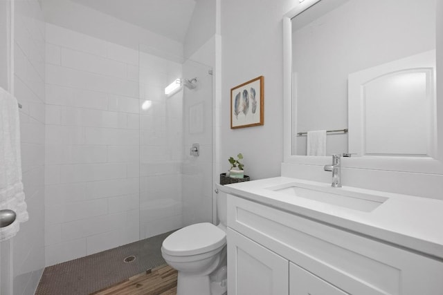 full bath with tiled shower, vanity, and toilet