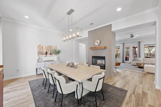 dining area with light wood-style floors, baseboards, visible vents, and ornamental molding