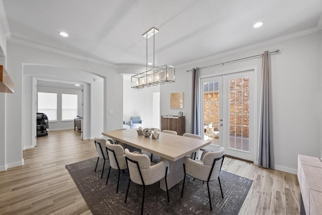 dining room featuring ornamental molding, french doors, arched walkways, and light wood-style floors