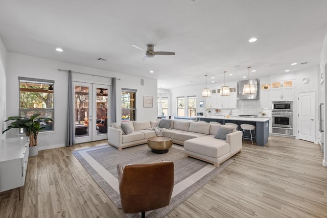 living area with light wood-type flooring, recessed lighting, and french doors