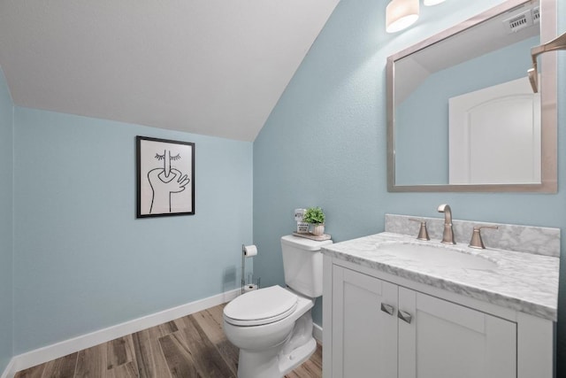 bathroom featuring baseboards, toilet, wood finished floors, vaulted ceiling, and vanity