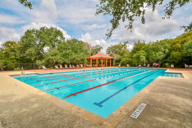 community pool with a patio area, fence, and a gazebo