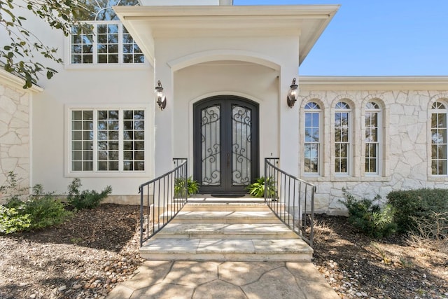 entrance to property featuring french doors and stucco siding