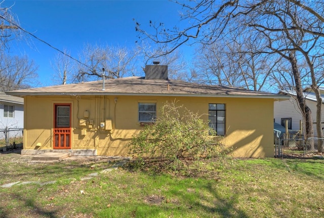 rear view of house with a chimney, fence, a lawn, and stucco siding