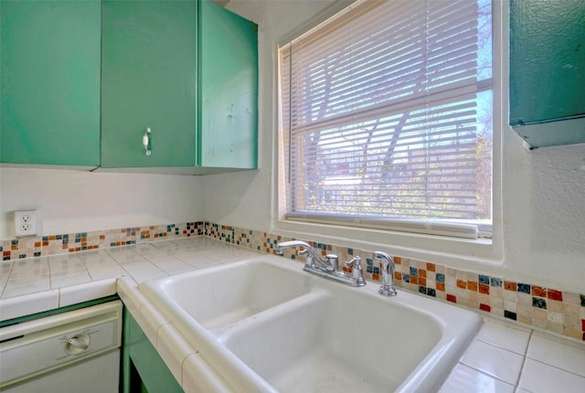 kitchen with tile countertops, tile patterned flooring, a sink, and green cabinetry