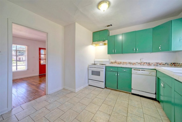 kitchen with under cabinet range hood, white appliances, a sink, visible vents, and green cabinetry