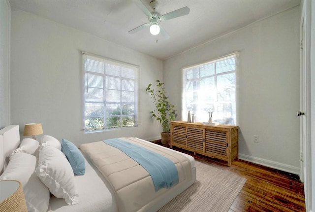 bedroom with multiple windows, wood finished floors, a ceiling fan, and baseboards