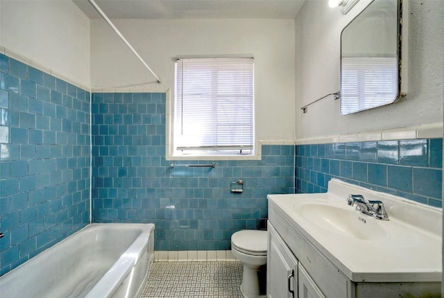 bathroom featuring tile patterned flooring, toilet, a wainscoted wall, vanity, and tile walls