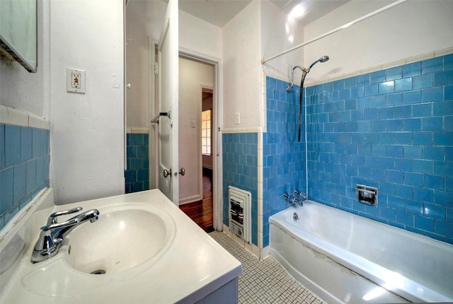 full bath featuring heating unit, tile patterned flooring, tub / shower combination, vanity, and tile walls