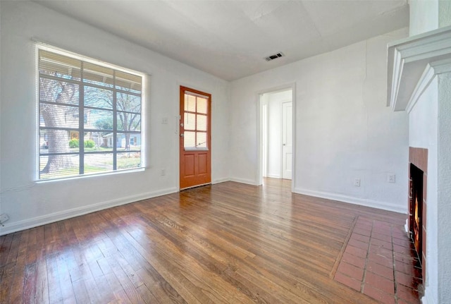 interior space with baseboards, a fireplace, visible vents, and hardwood / wood-style floors