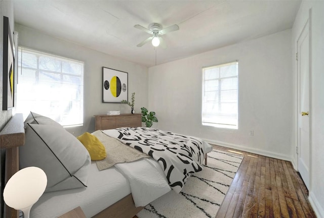 bedroom with hardwood / wood-style flooring, ceiling fan, multiple windows, and baseboards