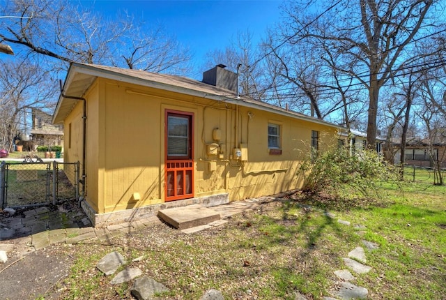 rear view of property featuring a chimney and fence