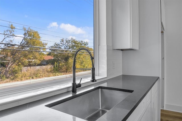 details with white cabinetry, backsplash, and a sink