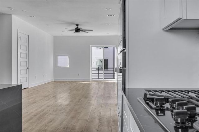 interior space with baseboards, light wood-type flooring, visible vents, and a ceiling fan