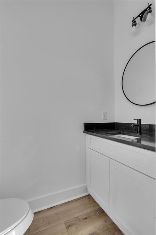 bathroom with baseboards, vanity, toilet, and wood finished floors