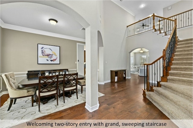 dining room featuring arched walkways, crown molding, stairway, and wood finished floors