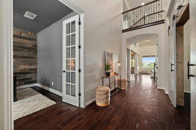 5305 Cardinal Flower Cv, Spicewood, TX 78669 - hallway with arched walkways, wood-type flooring, baseboards, wood walls, and a towering ceiling
