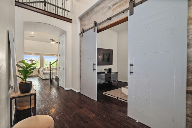 5305 Cardinal Flower Cv, Spicewood, TX 78669 - hallway featuring a barn door, a towering ceiling, wood-type flooring, baseboards, and arched walkways