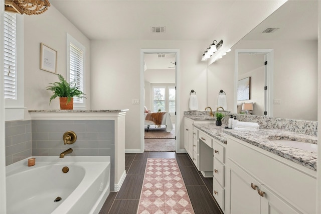 5305 Cardinal Flower Cv, Spicewood, TX 78669 - bathroom featuring connected bathroom, double vanity, a bath, and baseboards