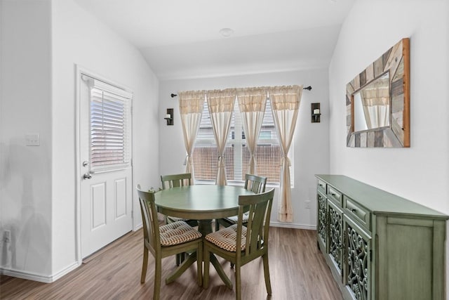 dining room with lofted ceiling, baseboards, and wood finished floors