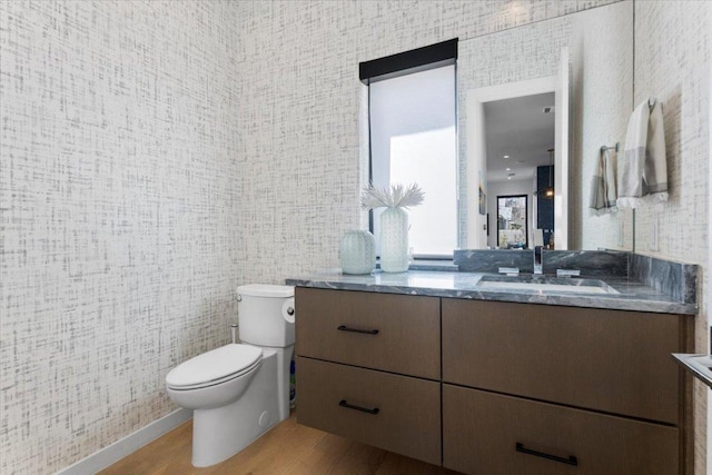 bathroom with toilet, wood finished floors, and vanity