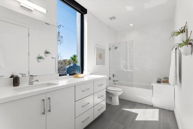 bathroom featuring double vanity, visible vents, shower / bathing tub combination, toilet, and a sink