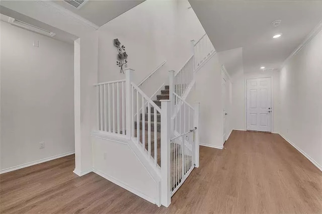 stairway featuring baseboards, visible vents, wood finished floors, crown molding, and recessed lighting