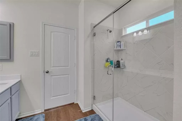 full bath with a shower stall, baseboards, wood finished floors, and vanity