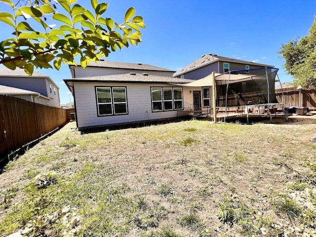 back of property with a trampoline and a fenced backyard