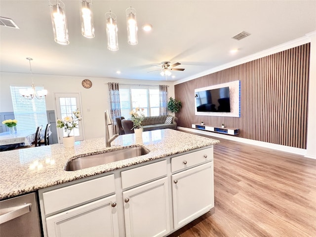 kitchen with wood finished floors, a sink, visible vents, white cabinetry, and pendant lighting