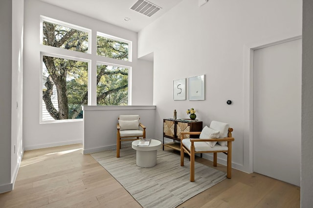 living area featuring baseboards, visible vents, a wealth of natural light, and wood finished floors