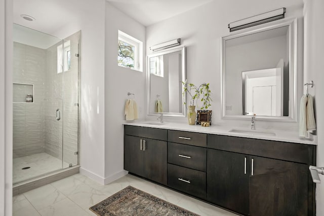 bathroom with double vanity, a stall shower, baseboards, marble finish floor, and a sink