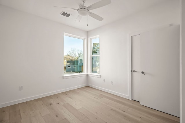 empty room featuring light wood-type flooring, visible vents, ceiling fan, and baseboards