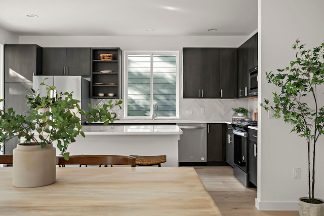 kitchen featuring electric range, light wood-style floors, light countertops, stainless steel dishwasher, and backsplash