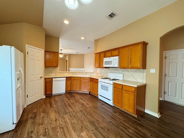 627 Columbine Ave, Cedar Park, TX 78613 - kitchen with white appliances, dark wood-type flooring, light countertops, brown cabinets, and arched walkways