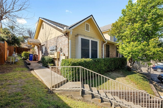 view of side of home with fence, a yard, and a shingled roof
