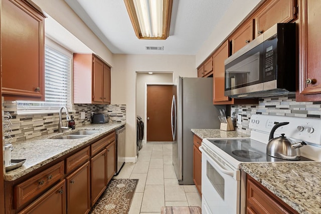 kitchen featuring light tile patterned floors, a sink, visible vents, appliances with stainless steel finishes, and backsplash