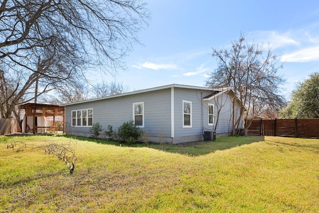 view of property exterior with cooling unit, fence, and a lawn