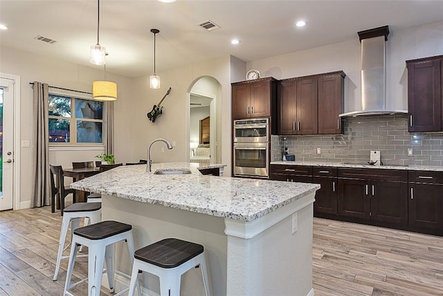 5608 Arroyo Rd, Austin, TX 78734 - kitchen featuring double oven, light wood-style floors, light stone countertops, a kitchen bar, and recessed lighting
