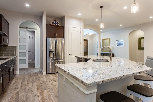 5608 Arroyo Rd, Austin, TX 78734 - kitchen with stainless steel appliances, arched walkways, light wood-type flooring, dark brown cabinetry, and light stone counters