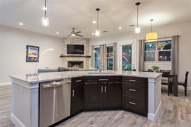 5608 Arroyo Rd, Austin, TX 78734 - kitchen with stainless steel dishwasher, a ceiling fan, open floor plan, light wood-style flooring, and a stone fireplace