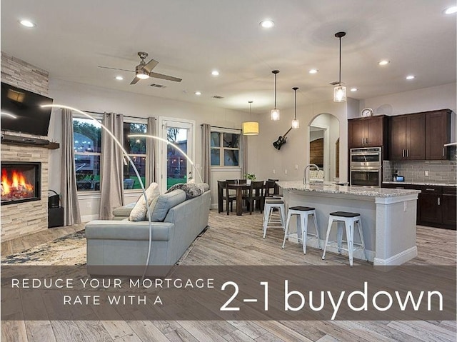 5608 Arroyo Rd, Austin, TX 78734 - kitchen with stainless steel double oven, dark brown cabinets, open floor plan, ceiling fan, and light wood-style floors