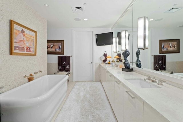 bathroom with tile patterned flooring, a sink, visible vents, a soaking tub, and double vanity