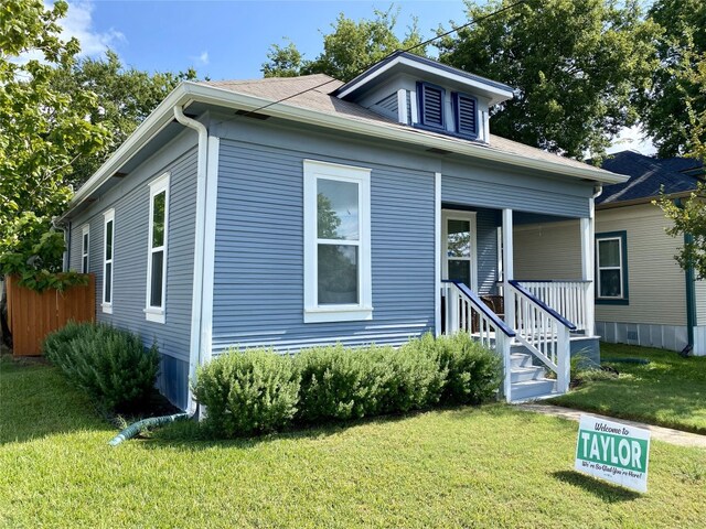 bungalow featuring covered porch and a front lawn