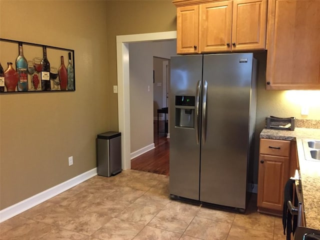 kitchen featuring light countertops, stainless steel fridge, a sink, and baseboards