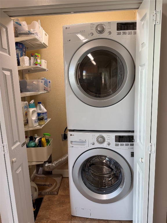 washroom with laundry area, tile patterned flooring, and stacked washer / dryer