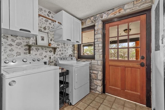 laundry room with a textured ceiling, light tile patterned flooring, cabinet space, and washer and dryer