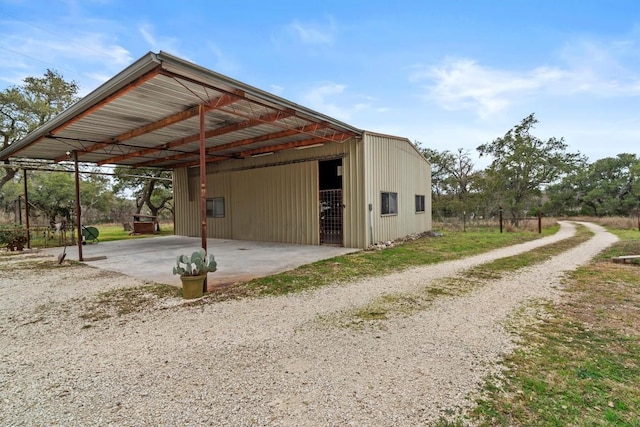 view of outdoor structure with a carport, gravel driveway, and an outdoor structure