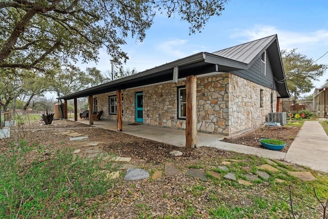 exterior space featuring metal roof, central AC, fence, a standing seam roof, and a patio area